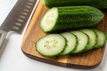 Fresh juicy cucumber slices on a wooden cutting board. Low calories raw vegetable snack of long green cucumbers. Healthy eating, harvest concept.
