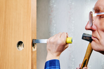 Chisel driven by hammer, cuts into wooden door frame to create mortise, with partially installed...