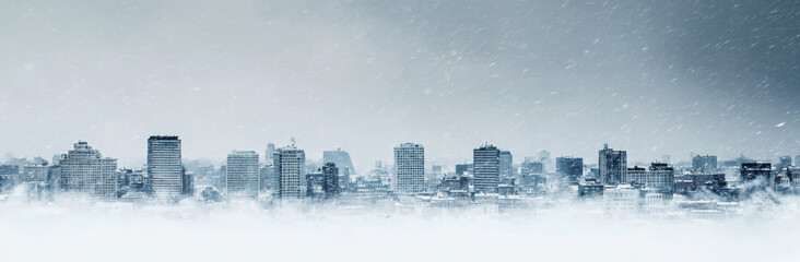 Obraz premium snowy city skyline during winter storm, showcasing tall buildings and cold atmosphere