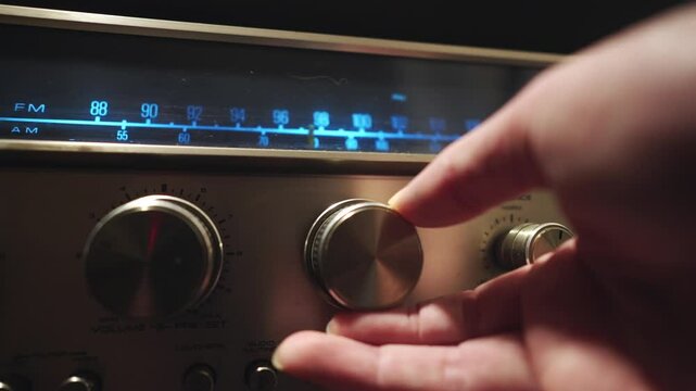 Hand turns illuminated tuning frequency dial on retro radio CLOSE-UP
