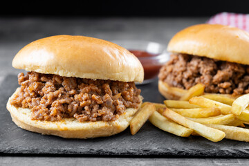 Traditional sloppy joe sandwich with french fries on wooden table