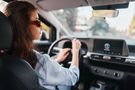Driving woman with hands on steering wheel, focusing on car's dashboard screen