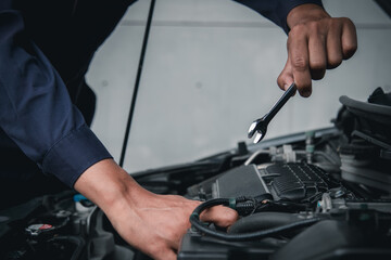 Mechanic using wrench while working on car engine outside the service center , Repair and service.
