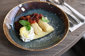 A traditional Czech sweet dish featuring potato dumplings, known as bramborové šišky, served with creamy quark cheese and ripe plums.