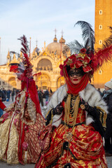 Fototapeta premium Venice, Italy - FEBRUARY 21, 2025: Venetians dressed in red masquerade clothes for carnival 