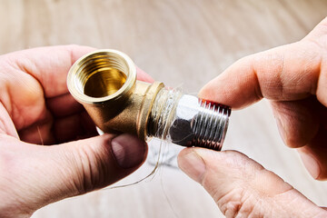 Hex nipple barrel reducer adapter is being sealed with plumbing hemp and screwed into brass elbow...