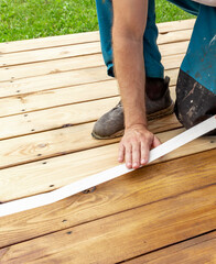 Man is laying down on a wooden deck and applying a white tape