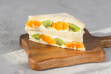 Korean sandwich with kiwi, orange and cream cheese on a table. Hard light. Asian dessert, street food.