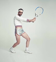 Portrait, man and retro as tennis player with racket, outfit and confidence on studio background. Male person, style and sportswear for vintage fashion, game or challenge in fitness, wellness or pose