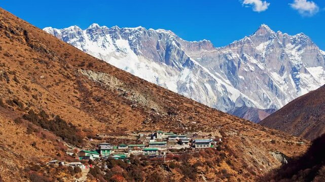 Towering Mount Everest rising above Shomare, revealing rugged Himalayan landscape with snow capped peaks surrounding traditional Nepalese mountain settlement