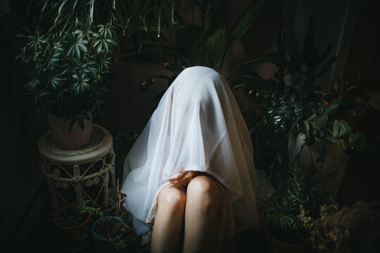 Mysterious Figure with Veil Among Indoor Plants