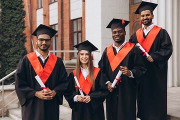 Group of Happy Graduates in Caps and Gowns Celebrating Graduation Day Outdoors