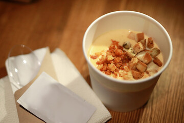 delicious cheese soup with croutons in a plastic cup in a cafe