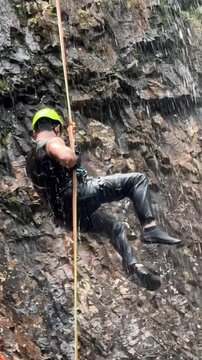homem mochileiro faz rapel em cachoeira 