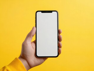 Hand holding phone with blank screen on yellow background