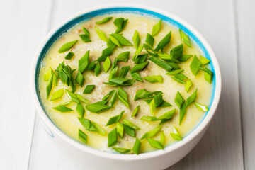 Healthy food, liver pate with butter and green onions in a bowl on light table