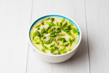 Healthy food, liver pate with butter and green onions in a bowl on light table