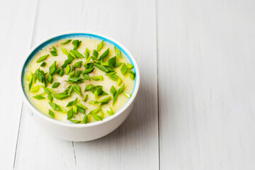 Healthy food, liver pate with butter and green onions in a bowl on light table