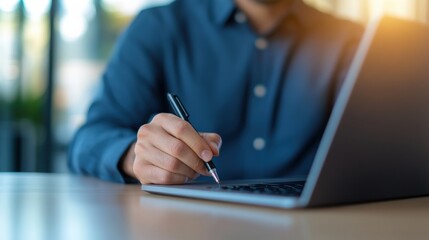 man using pen on laptop computer.