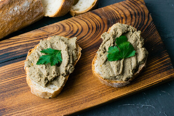 Healthy food, sandwiches with liver pate, parsley and crispy baguette on a dark wooden kitchen...