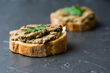 Healthy food, sandwiches with liver pate, parsley and crispy baguette close-up on a dark background