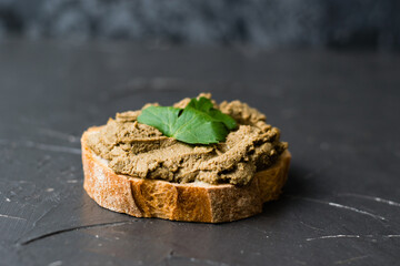 Healthy food, delicious and appetizing sandwich with beef liver, parsley and aromatic baguette with crispy crust close-up on a dark background