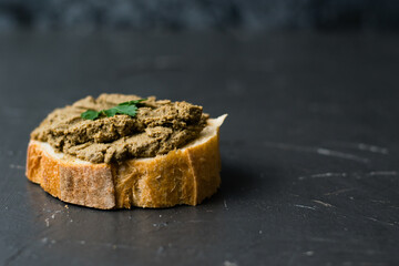 Healthy food, delicious and appetizing sandwich with beef liver, parsley and aromatic baguette with crispy crust close-up on a dark background
