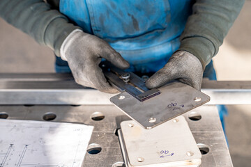Metalworker measuring metal part with vernier caliper in workshop