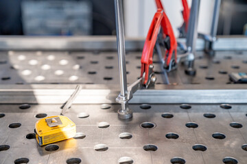 Fototapeta premium Welding table with clamps, measuring tape, and metal profiles in workshop