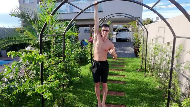 homem positivo pendurado em barra para treino de calistenia 