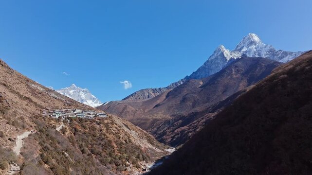 Traditional Nepalese village of Shomare, Ama Dablam revealing pristine Himalayan landscape, snow capped peak rising over verdant valley under azure sky