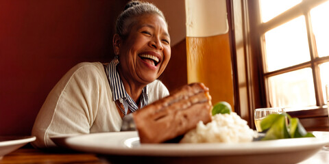 Black female pensioner laughing and enjoying a meal out with friends