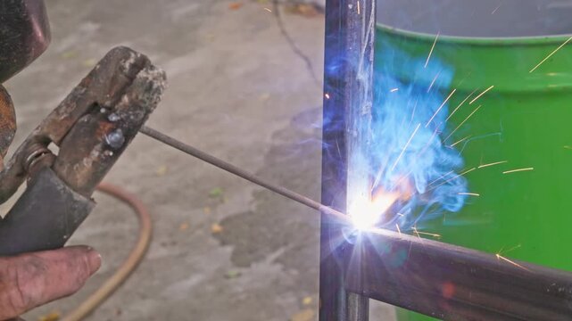closeup view of stick welding of square steel tubes angle connection