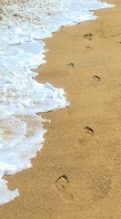 Footprints of human feet in the sand near the water on the beach