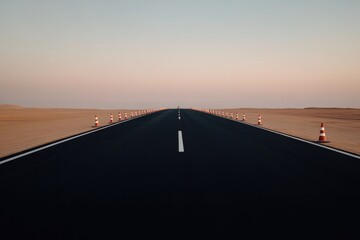Fototapeta premium Endless road stretches into horizon, blending with soft pastel s