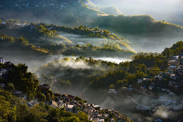 Morning scenic view of hilly Aizawl city (Mizoram) with clouds and sun rays among the hills.