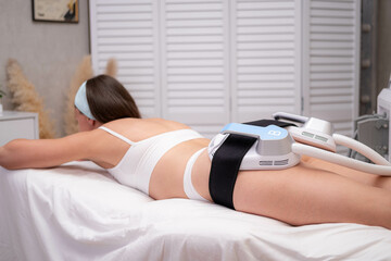 professional electrostimulation session, close up view o therapist applying EMS device on woman in...