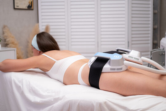 professional electrostimulation session, close up view o therapist applying EMS device on woman in modern clinic, muscle toning, body sculpting, fitness industry