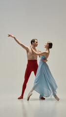 Fototapeta premium Ballet partners moving in perfect unison, gazes locked, hands delicately connected, elegance captured in fluid pose against white studio background. Concept of beauty, trust, synchronization, art.