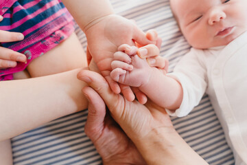 Baby's hand into parents hands and older child. Family hands together happiness concept.