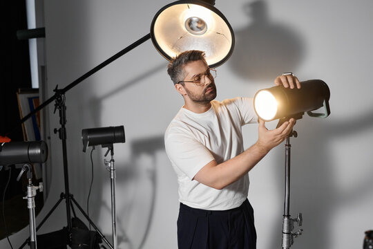 Creative professional adjusting lighting equipment in modern studio space