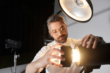 Creative man adjusting lighting equipment in a modern photography studio