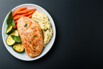 Grilled chicken breast with mashed potatoes, zucchini, and carrots on plate