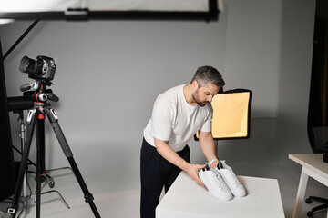 Man arranging sneakers in a modern studio setting while capturing striking visuals