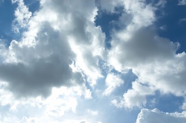 Thick clouds behind the hot sun. Beautiful white clouds in the bright blue sky as a natural concept.