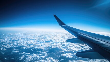 The silhouette of an airplane wing against a bright blue sky, soaring above a blanket of clouds, symbolizing a flight to distant destinations.