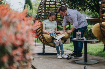 A boy with Down syndrome assists a disabled girl with reading a book while sitting outdoors in a...