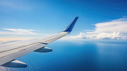 Fototapeta premium A commercial airplane cruising over the ocean, with the wingtip visible in the foreground, representing the distance covered in a transatlantic flight.
