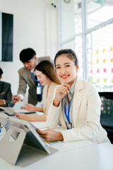 Woman in a white jacket is smiling at the camera while holding a tablet