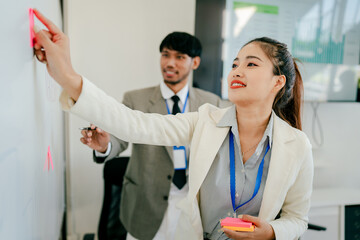 Obraz premium Woman and a man are working together on a whiteboard